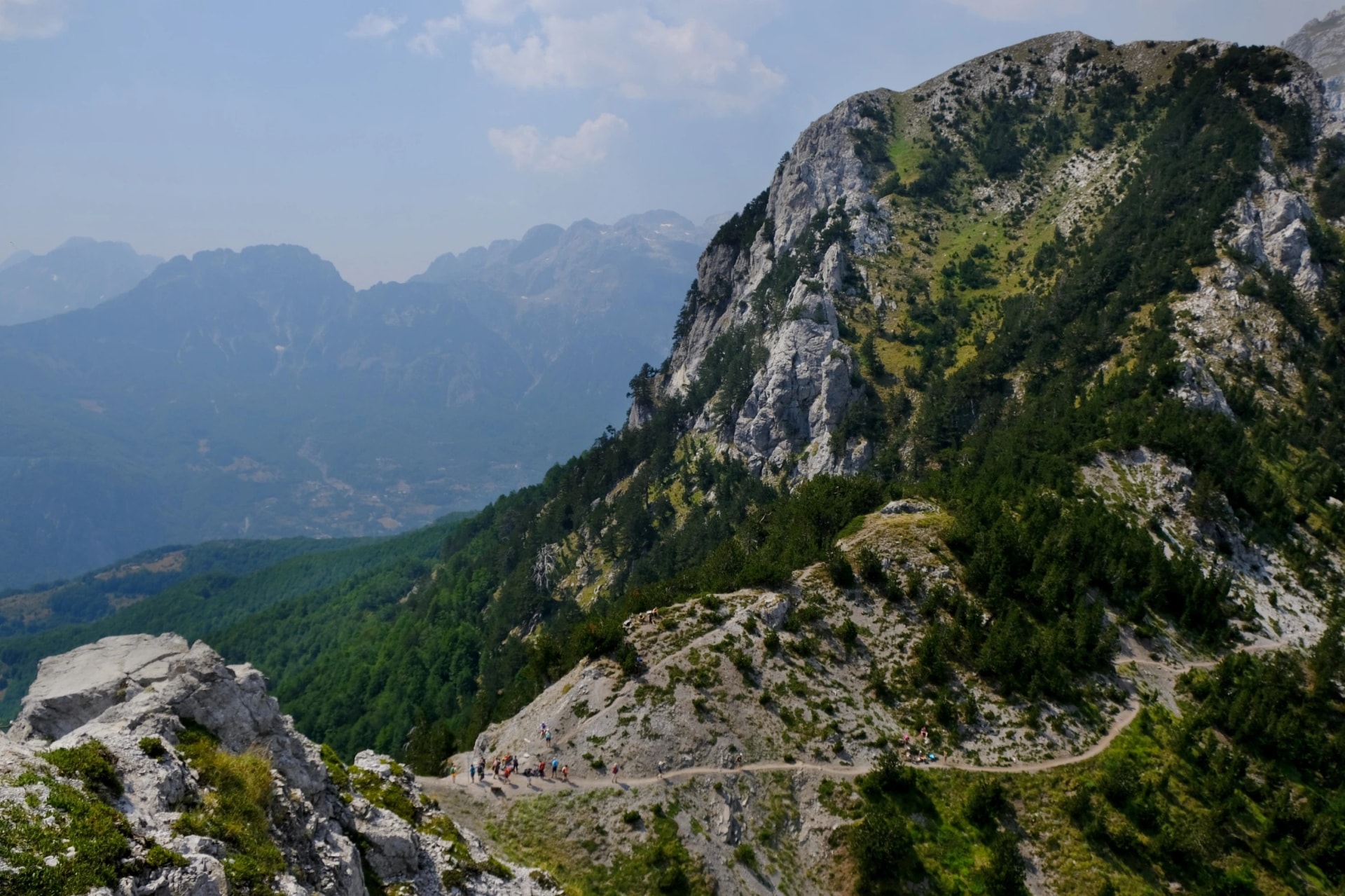 Valbona Pass (Albanian: Qafa e Valbones) on trail from Theth Valley to Valbona Valley in Albanian Alps. Sihouettes of tourists on pass. It is one of the most beautiful high mountain trails.